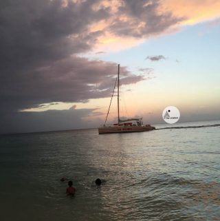 picture of kids in the ocean and a boat in the background